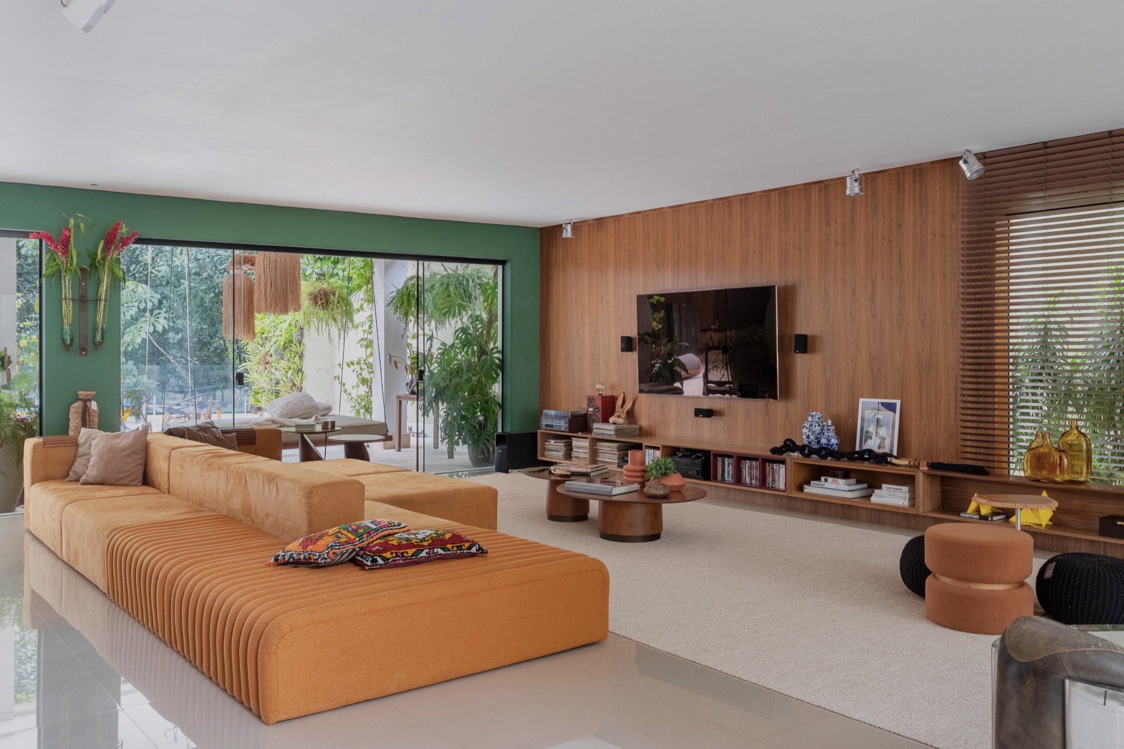 Sala de estar da Residência Eduardo Sterblitch, com sofá modular terracota e parede verde